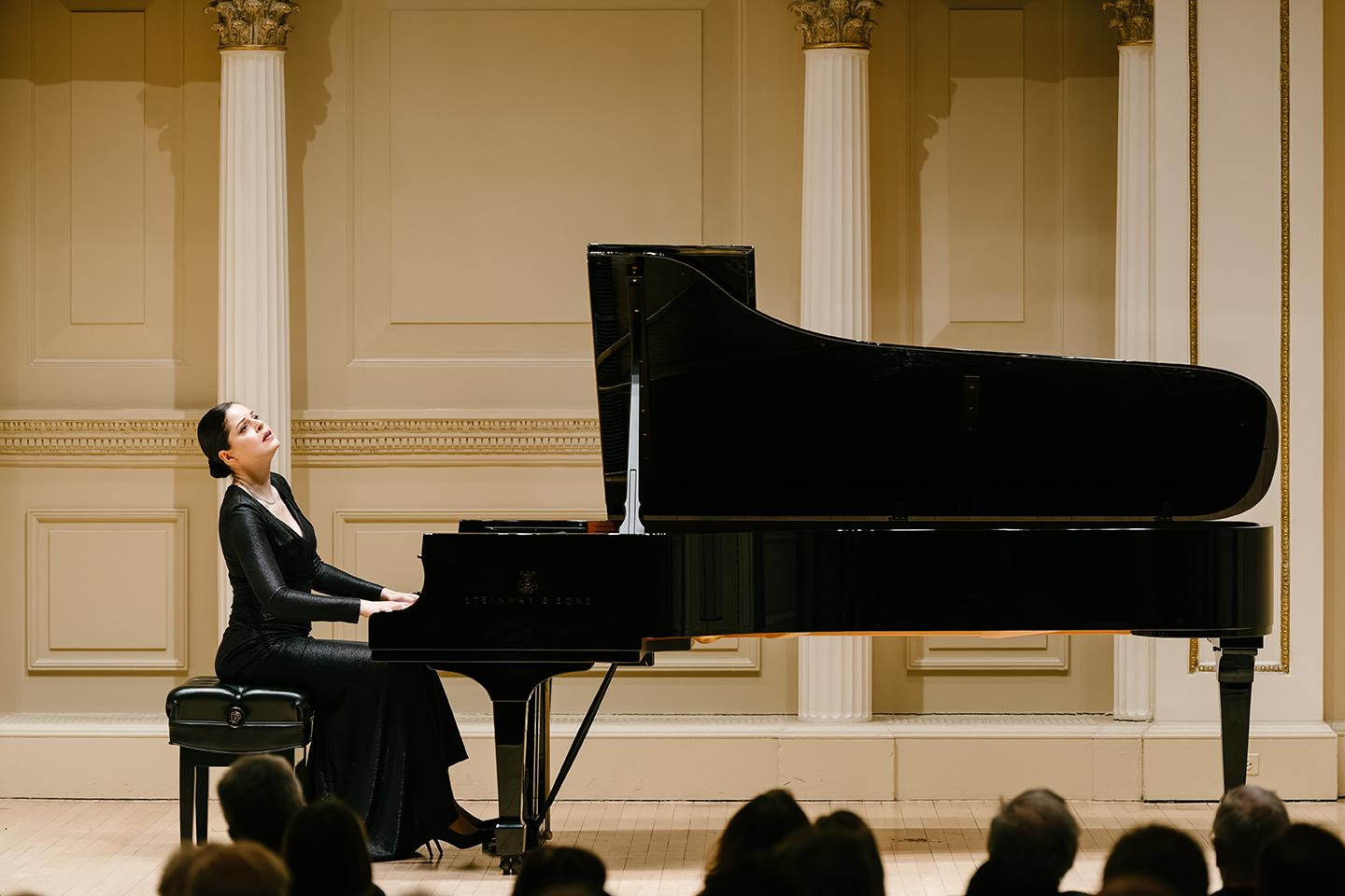 A woman in a black dress playing a grand piano