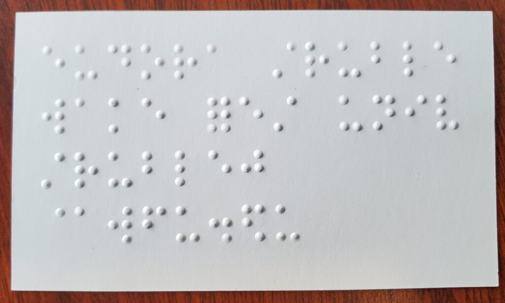 The back of a business card, showing the raised bumps of braille.