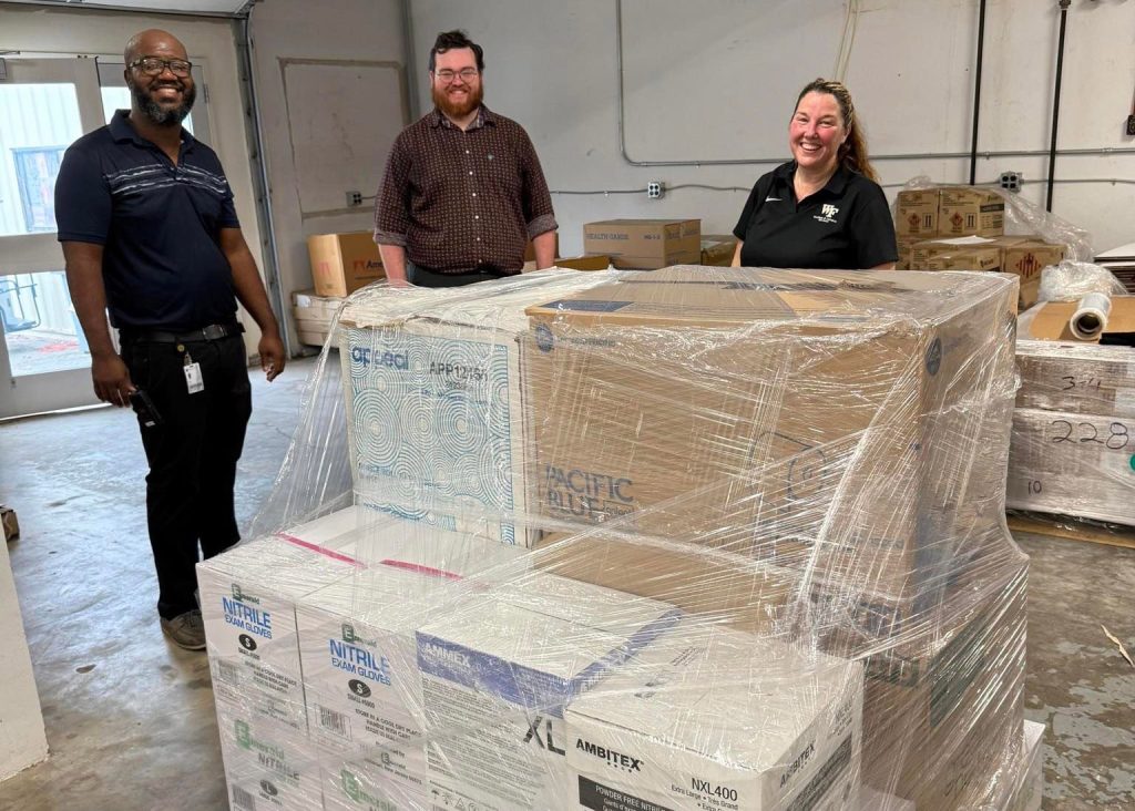 Wake Forest employees stand with a pallet of donated supplies.